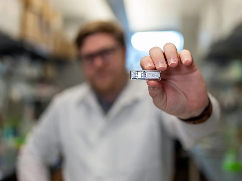 莱斯大学博士生克里斯·赖特手持一厘米长的装置,能在生产医疗药物时保持工程细胞的氧合和生命。